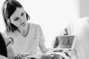 Fizjoterapeutka pokazuje pacjentce na tablecie wykres pracy mięśni dna miednicy podczas EMG biofeedback
