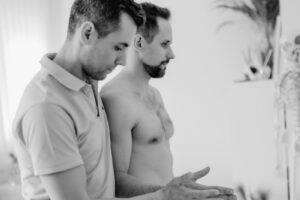 Fizjoterapeuta stoi za pacjentem i tłumaczy mu wynik badania barku