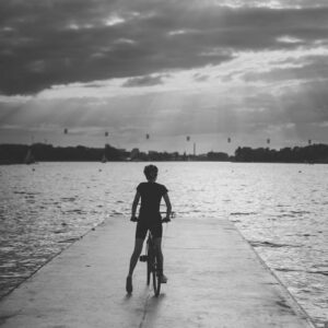 Rowerzystka z rowerem na końcu molo, widziana od tyłu